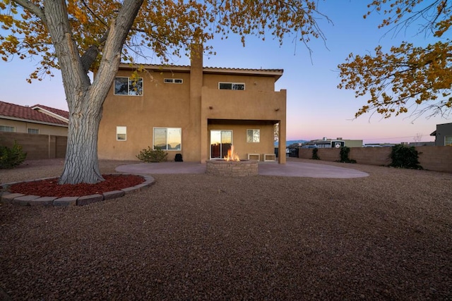 9801 Basha St NW, Albuquerque, NM 87114 - back of house at dusk featuring a patio area, a chimney, stucco siding, and a fenced backyard