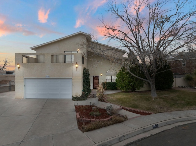 view of front of house featuring a garage, driveway, a lawn, and stucco siding