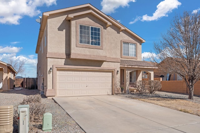 traditional-style home featuring driveway, an attached garage, fence, and stucco siding