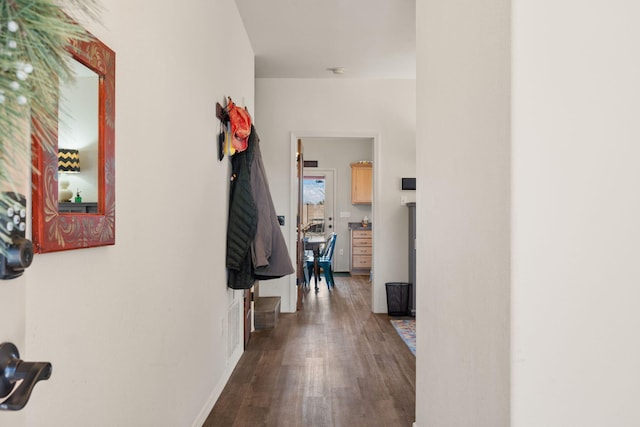 hall featuring dark wood-type flooring and baseboards