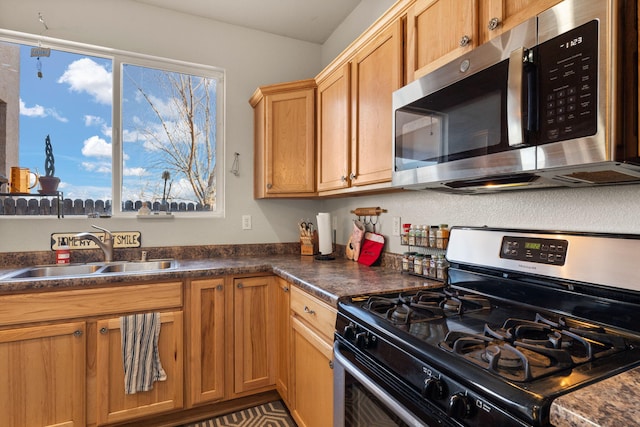 kitchen featuring stainless steel appliances, dark countertops, and a sink