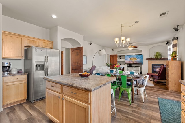 kitchen with visible vents, a tile fireplace, stainless steel fridge with ice dispenser, open floor plan, and a center island