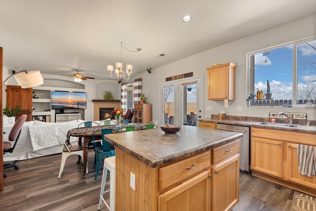 kitchen with open floor plan, dark countertops, a sink, and dishwasher