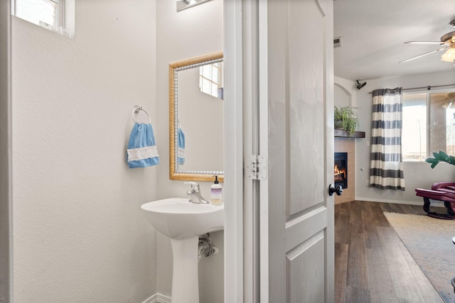 bathroom with ceiling fan, a tile fireplace, wood finished floors, and visible vents