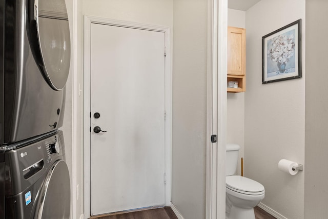 washroom with laundry area, stacked washer / dryer, dark wood finished floors, and baseboards