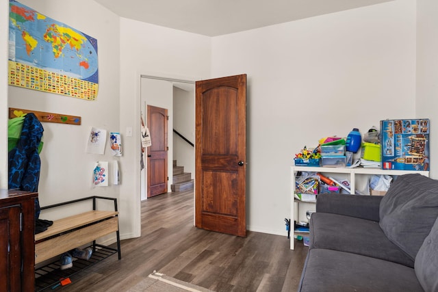 living area with dark wood finished floors, baseboards, and stairs