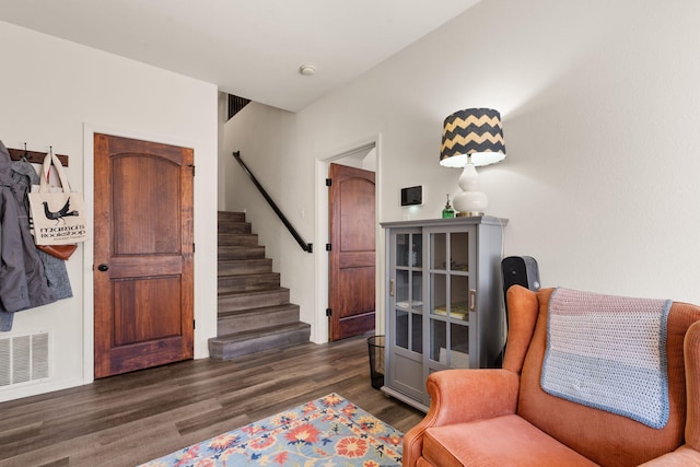 sitting room featuring dark wood-type flooring, visible vents, and stairs