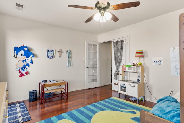 bedroom featuring a ceiling fan, dark wood-style flooring, visible vents, and baseboards