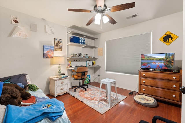 office space featuring a ceiling fan, visible vents, and wood finished floors