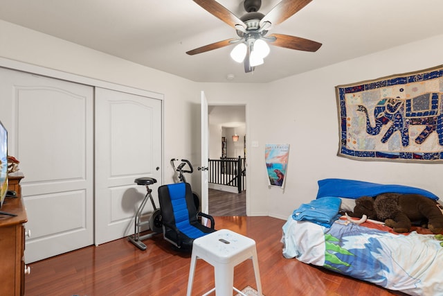 bedroom with a closet, ceiling fan, baseboards, and wood finished floors