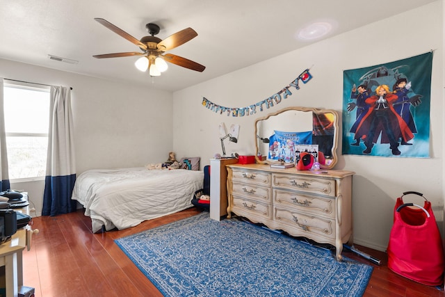 bedroom featuring dark wood-style floors, visible vents, and a ceiling fan