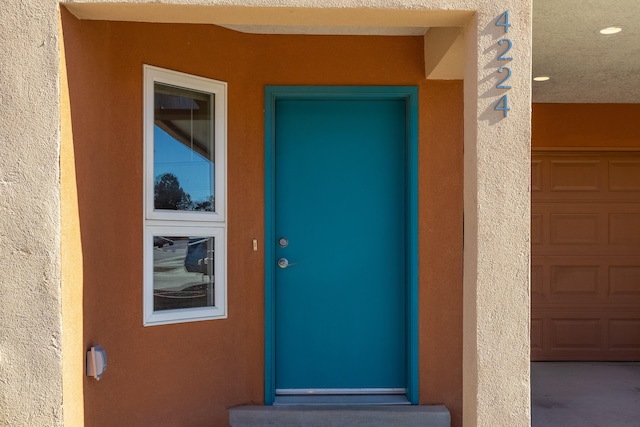 property entrance with a garage and stucco siding