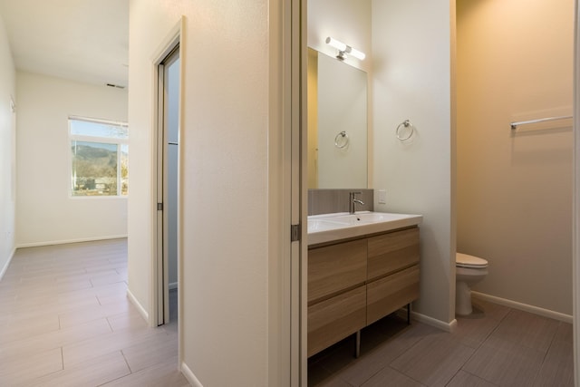 bathroom featuring wood finish floors, visible vents, toilet, vanity, and baseboards