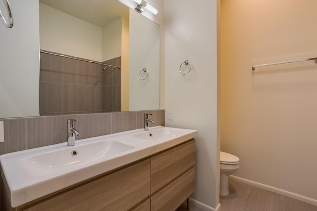 bathroom with baseboards, a sink, toilet, and double vanity