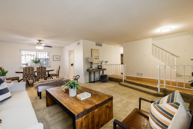 living room with visible vents, light carpet, and stairs