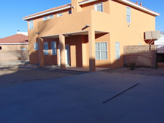 rear view of house featuring fence and stucco siding