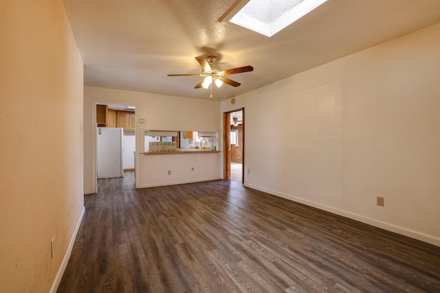 unfurnished living room with a skylight, baseboards, dark wood finished floors, and a ceiling fan