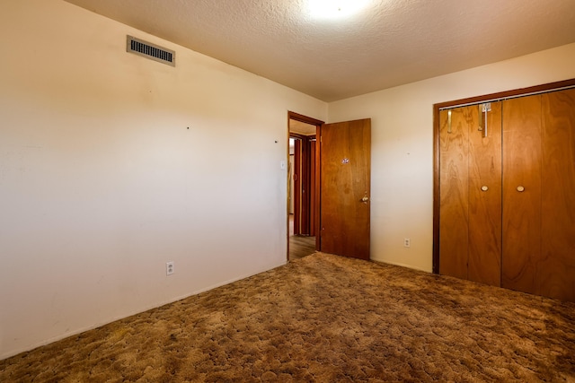 unfurnished bedroom with carpet floors, a closet, visible vents, and a textured ceiling