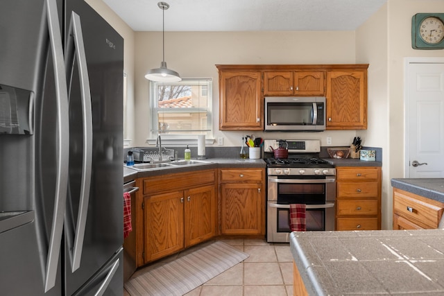 kitchen featuring stainless steel appliances, brown cabinetry, light tile patterned flooring, and a sink