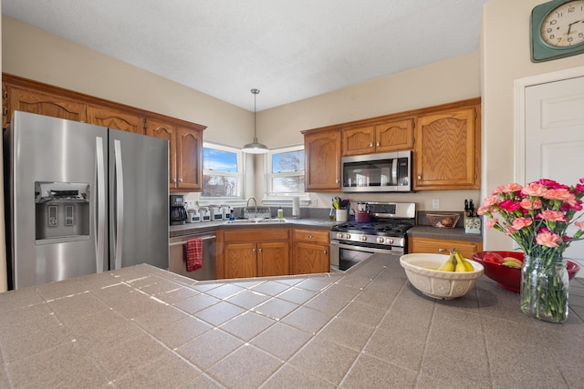 kitchen with stainless steel appliances, brown cabinets, decorative light fixtures, and a sink