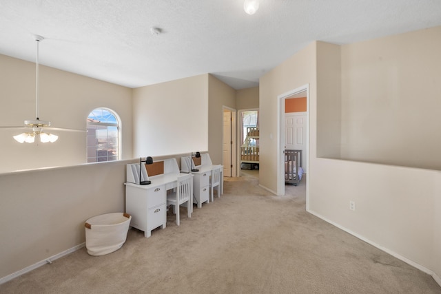 interior space featuring light carpet, baseboards, and a textured ceiling