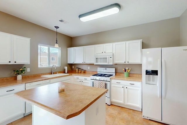 kitchen featuring pendant lighting, white appliances, light countertops, and a sink