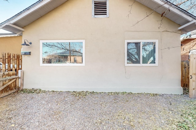 view of side of home featuring fence and stucco siding