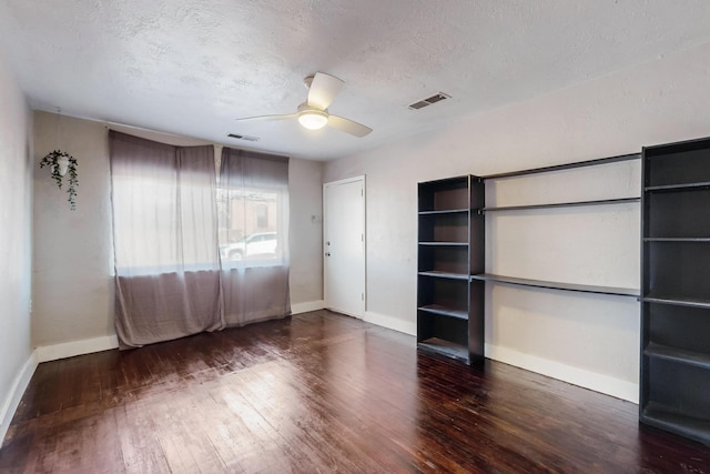 spare room featuring dark wood-type flooring, visible vents, a textured ceiling, and baseboards