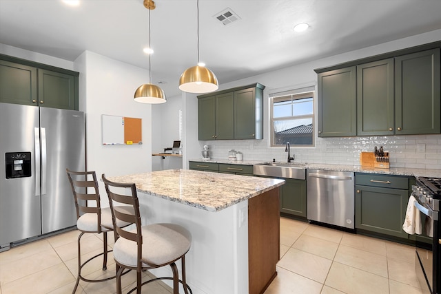 kitchen featuring visible vents, a kitchen island, light stone counters, stainless steel appliances, and pendant lighting