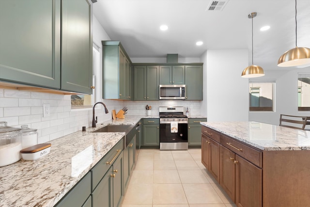 kitchen featuring stainless steel appliances, a sink, visible vents, light stone countertops, and pendant lighting