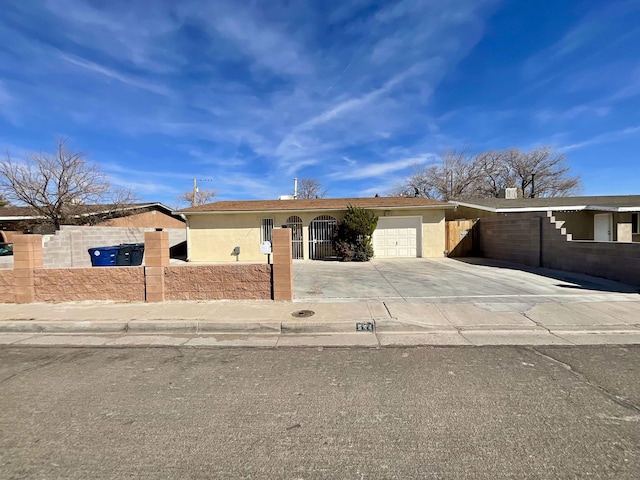 ranch-style home featuring an attached garage, fence, concrete driveway, and stucco siding