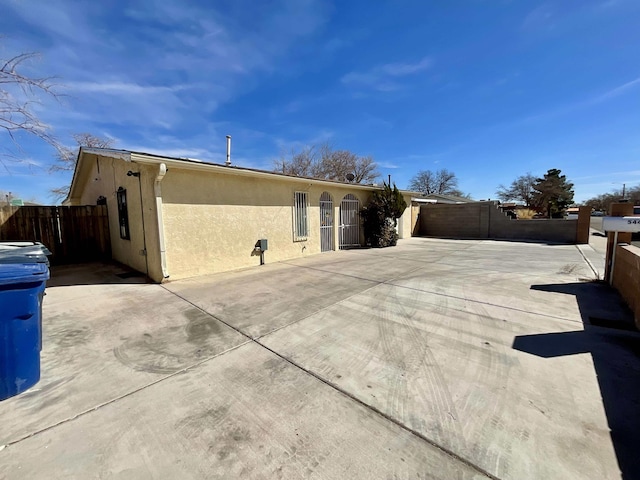 view of property exterior with a patio area, fence, and stucco siding