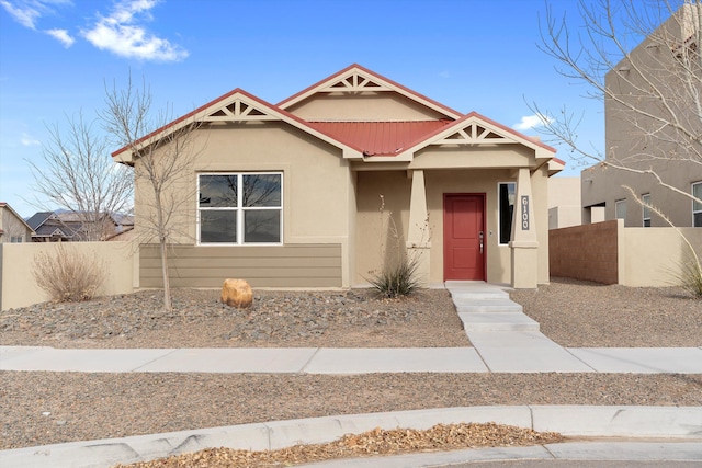 view of front of property featuring fence, metal roof, and stucco siding