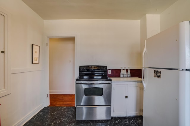 kitchen featuring white cabinetry, freestanding refrigerator, and stainless steel electric stove