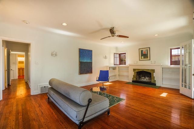 living area with a wealth of natural light, visible vents, a fireplace, and wood finished floors