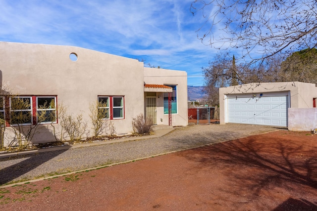 view of front of home featuring a garage, driveway, fence, and stucco siding