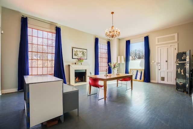 dining room with a chandelier, dark wood-style flooring, a fireplace with flush hearth, and baseboards