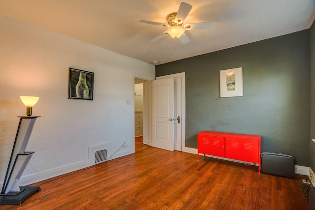 interior space featuring baseboards, visible vents, ceiling fan, and wood finished floors