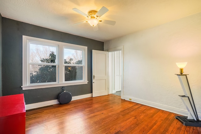 unfurnished bedroom featuring wood finished floors, a ceiling fan, and baseboards