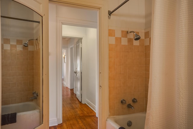 bathroom featuring wood finished floors, shower / bath combo with shower curtain, and baseboards