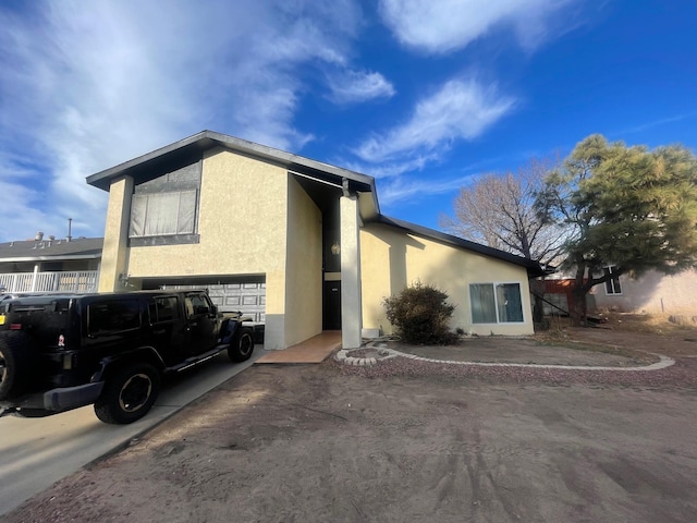 exterior space with an attached garage, concrete driveway, and stucco siding