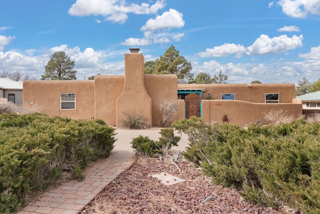 view of front of property featuring a fenced front yard, a chimney, a gate, and stucco siding