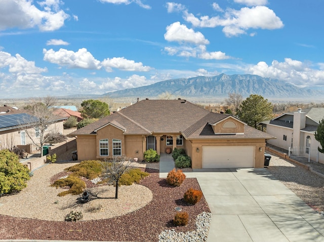 single story home with driveway, an attached garage, a mountain view, and stucco siding