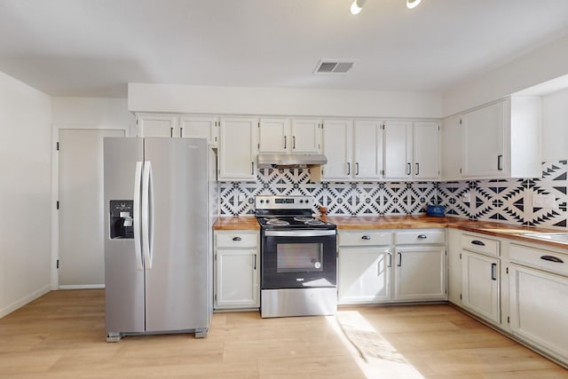 kitchen featuring under cabinet range hood, wood counters, visible vents, appliances with stainless steel finishes, and tasteful backsplash