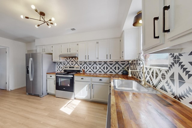 kitchen with stainless steel appliances, butcher block counters, a sink, and under cabinet range hood