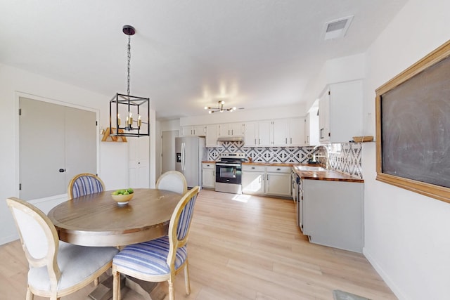 dining area featuring light wood-type flooring, baseboards, and visible vents