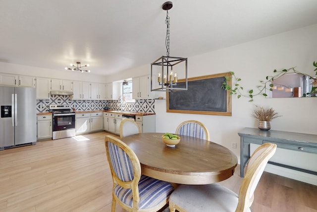 dining area featuring light wood finished floors and a chandelier