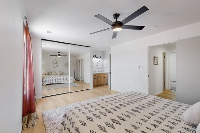 bedroom featuring light wood finished floors, ceiling fan, visible vents, and connected bathroom