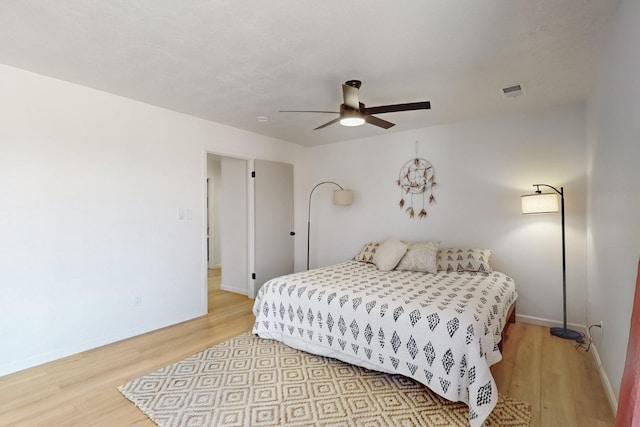 bedroom with ceiling fan, light wood-type flooring, visible vents, and baseboards