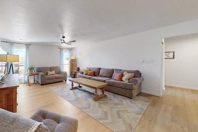 living area with baseboards, ceiling fan, and light wood finished floors